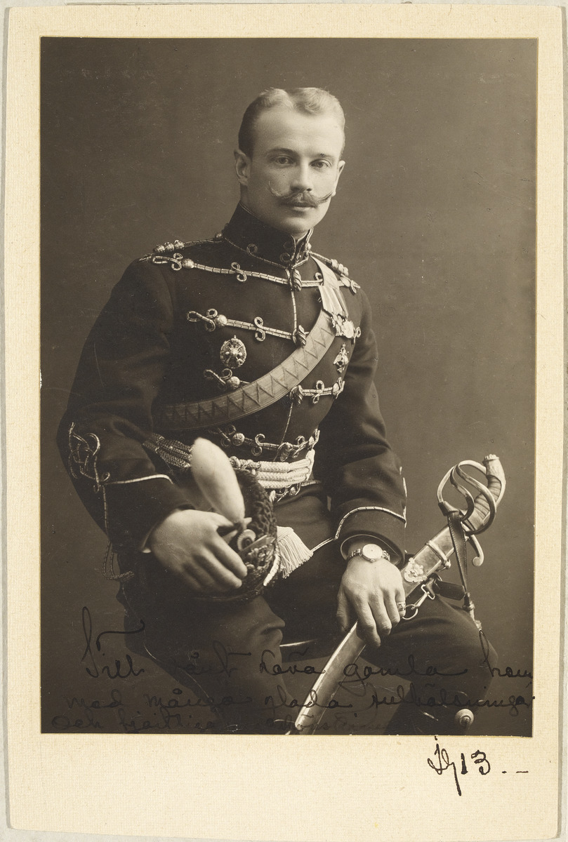 Aejmelaeus-Äimä seated in Russian Imperial cavalry officer’s uniform in 1913, shako in his right hand, saber in his left.